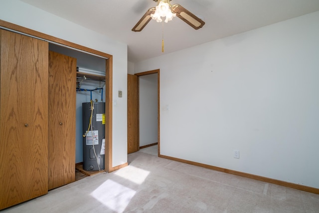 unfurnished bedroom featuring ceiling fan, electric water heater, light colored carpet, and a closet