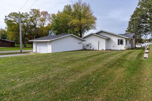 view of home's exterior featuring a garage, a lawn, and an outbuilding