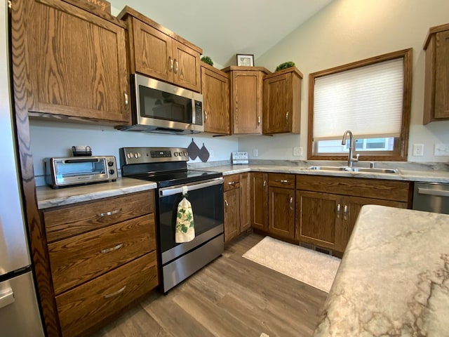 kitchen with vaulted ceiling, sink, dark wood-type flooring, and stainless steel appliances