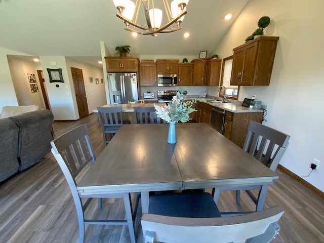 dining area with a notable chandelier, lofted ceiling, sink, and dark hardwood / wood-style flooring