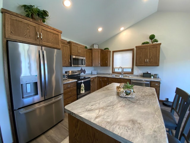 kitchen featuring lofted ceiling, sink, a kitchen island, hardwood / wood-style flooring, and appliances with stainless steel finishes