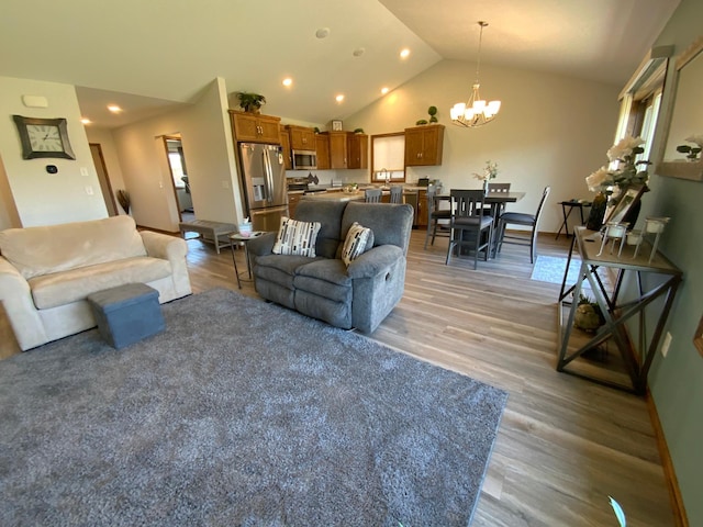 living room with an inviting chandelier, lofted ceiling, and light hardwood / wood-style floors