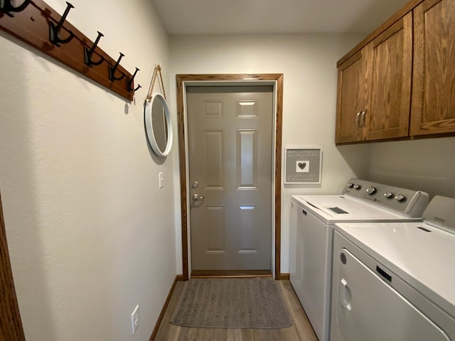 laundry room with cabinets, light hardwood / wood-style floors, and washing machine and dryer