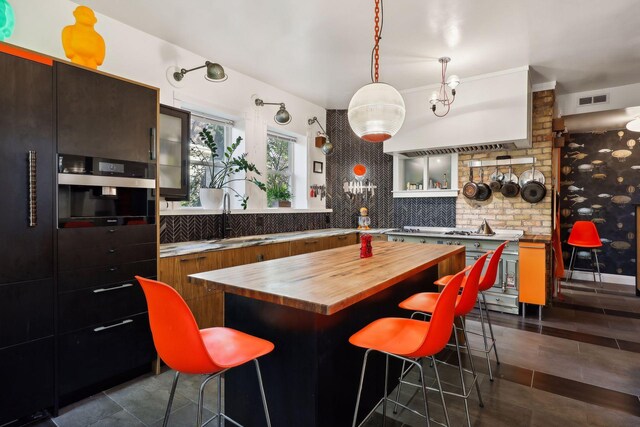1920 Pillsbury Ave S, Minneapolis, MN 55403 - kitchen featuring butcher block counters, a sink, a breakfast bar area, a kitchen island, and dark tile patterned flooring