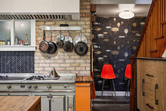 1920 Pillsbury Ave S, Minneapolis, MN 55403 - kitchen with wooden counters, dark tile patterned floors, ventilation hood, stainless steel range, and brown cabinetry