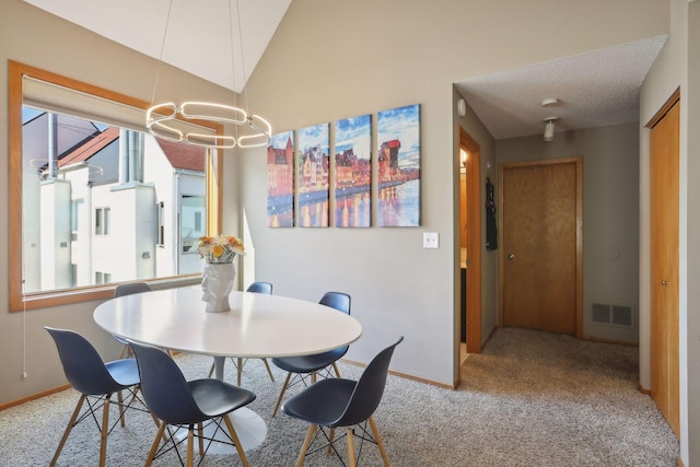 dining room featuring light colored carpet, a textured ceiling, lofted ceiling, and a chandelier