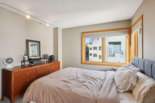 bedroom featuring carpet flooring, rail lighting, and a textured ceiling