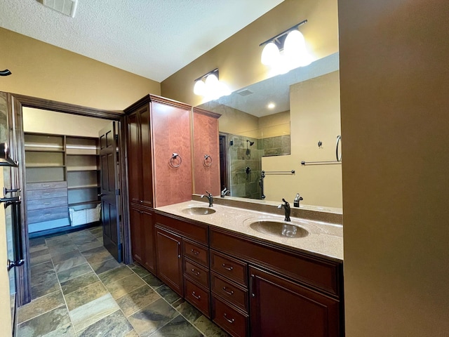 bathroom with vanity, an enclosed shower, and a textured ceiling