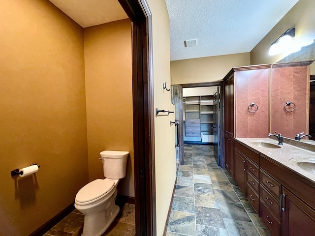 bathroom with toilet, a textured ceiling, and vanity