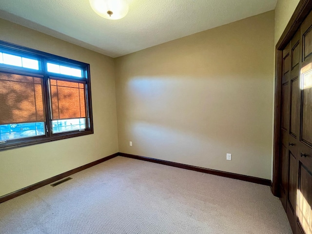 carpeted spare room with a textured ceiling