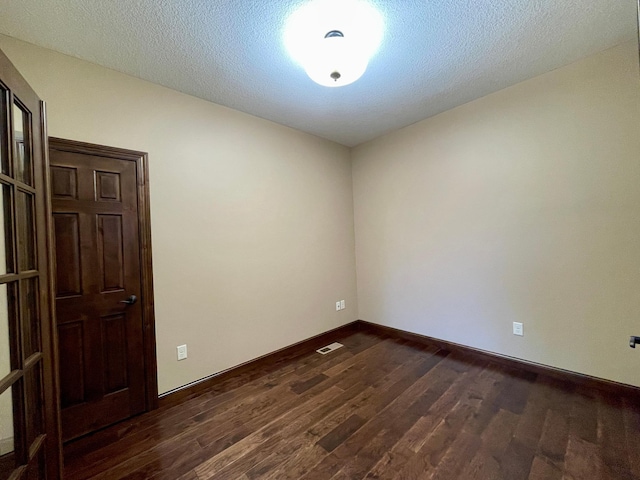 empty room with a textured ceiling and dark hardwood / wood-style floors