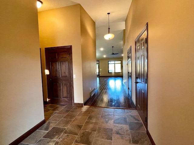 corridor with high vaulted ceiling and dark hardwood / wood-style flooring