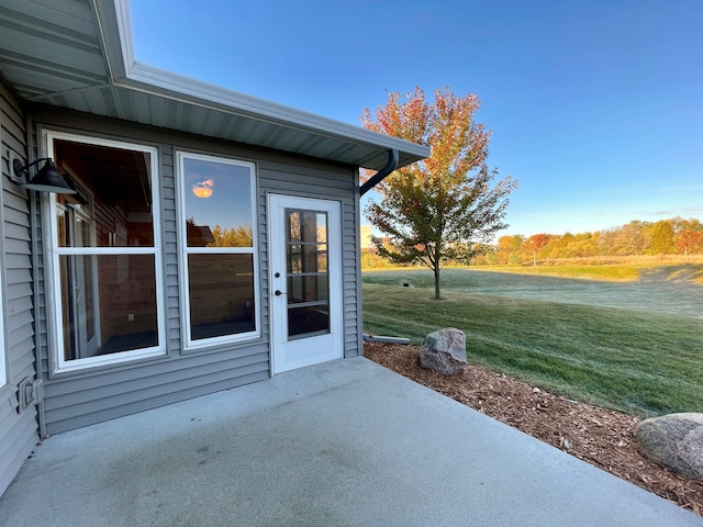 view of exterior entry featuring a patio and a lawn