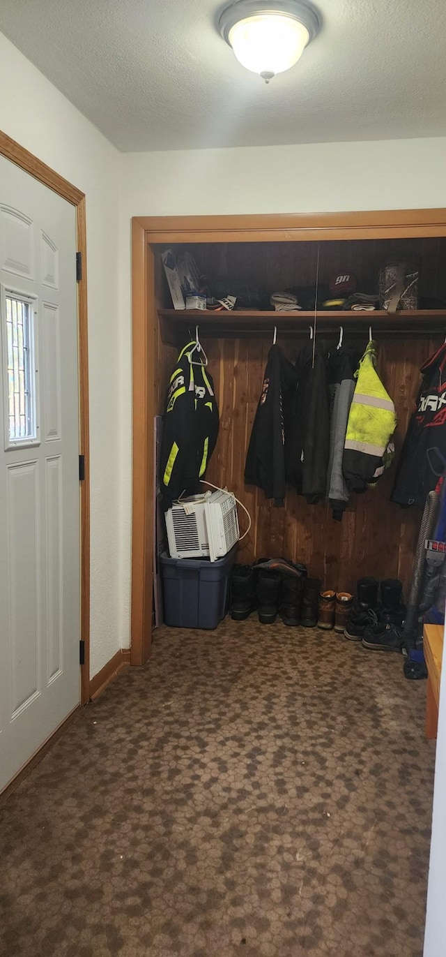 mudroom with dark carpet and a textured ceiling