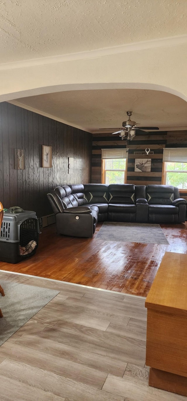 unfurnished living room with wooden walls, ceiling fan, hardwood / wood-style flooring, and a textured ceiling