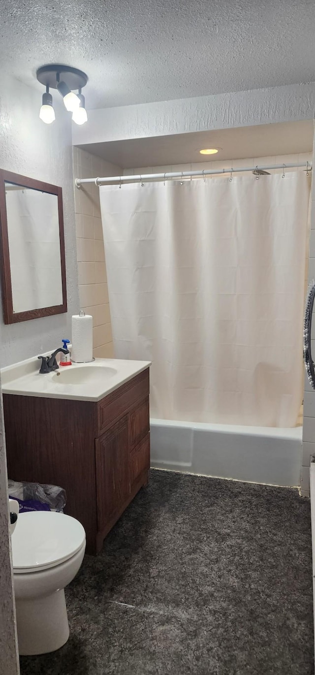 full bathroom featuring shower / bath combination with curtain, a textured ceiling, vanity, and toilet