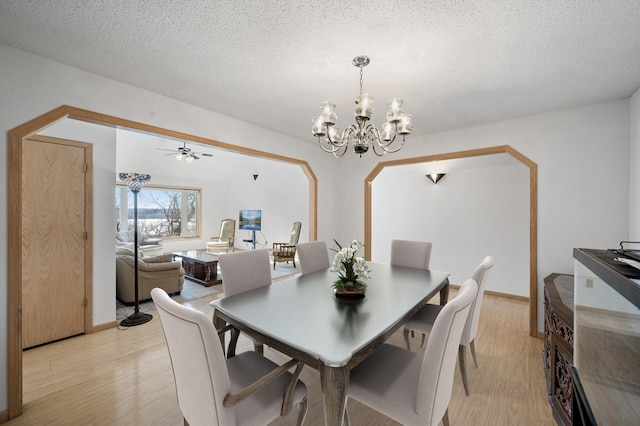 dining space with a textured ceiling, a chandelier, and light wood-type flooring