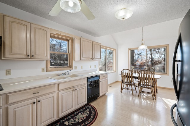 kitchen featuring light brown cabinetry, sink, pendant lighting, light hardwood / wood-style floors, and black appliances