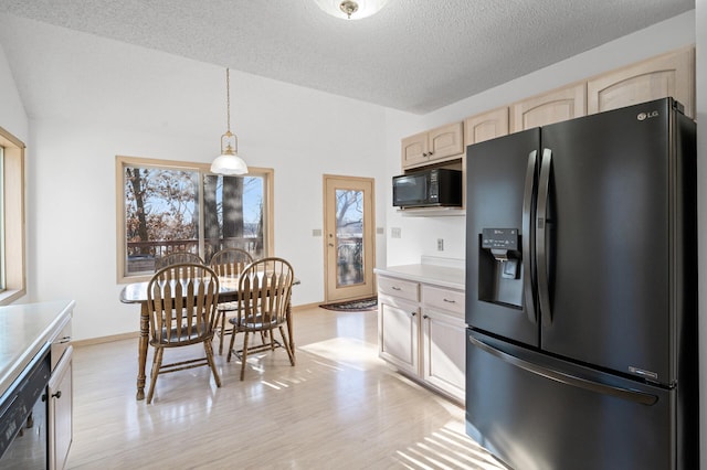 kitchen featuring hanging light fixtures, black appliances, light hardwood / wood-style floors, and a textured ceiling