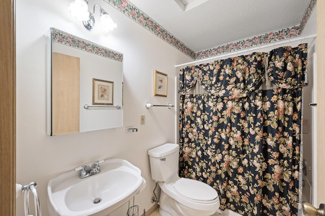 bathroom featuring toilet, curtained shower, sink, and a textured ceiling