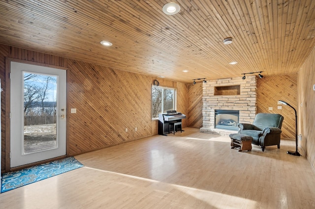 unfurnished living room with hardwood / wood-style floors, a fireplace, wooden ceiling, and wooden walls