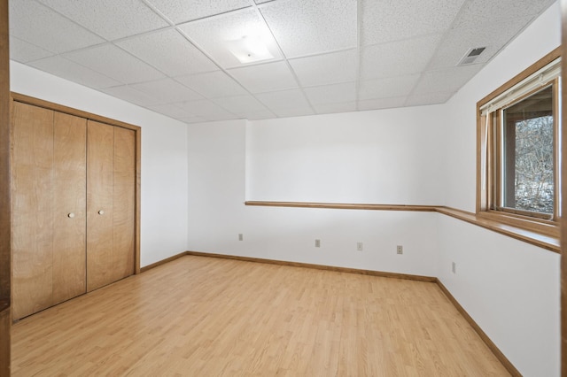 unfurnished bedroom featuring hardwood / wood-style flooring, a paneled ceiling, and a closet