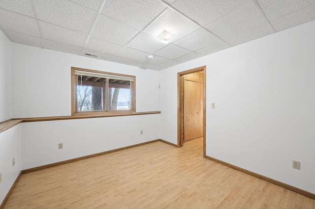 unfurnished room with light hardwood / wood-style floors and a drop ceiling