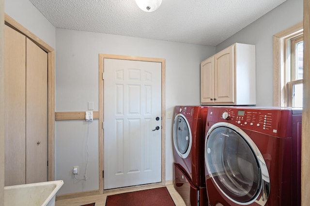 laundry area with cabinets, washer and dryer, and a textured ceiling