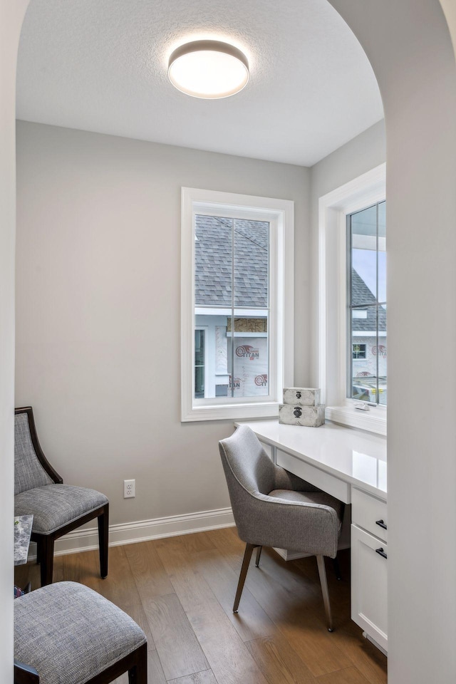 home office with a textured ceiling and light wood-type flooring