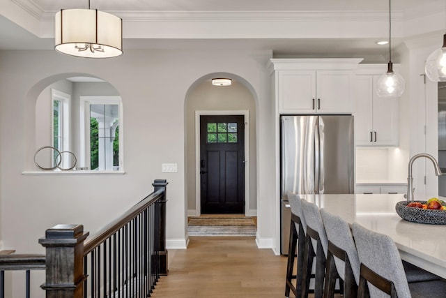 kitchen with white cabinets, stainless steel refrigerator, light hardwood / wood-style flooring, and pendant lighting