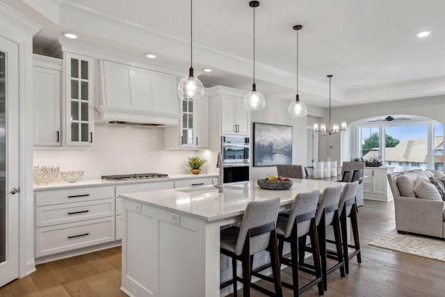 kitchen with white cabinetry, dark hardwood / wood-style floors, appliances with stainless steel finishes, and a kitchen island with sink