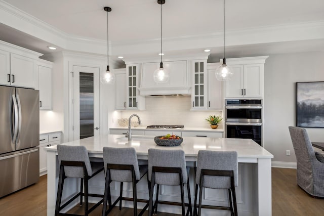 kitchen featuring an island with sink, dark hardwood / wood-style floors, decorative light fixtures, and stainless steel appliances