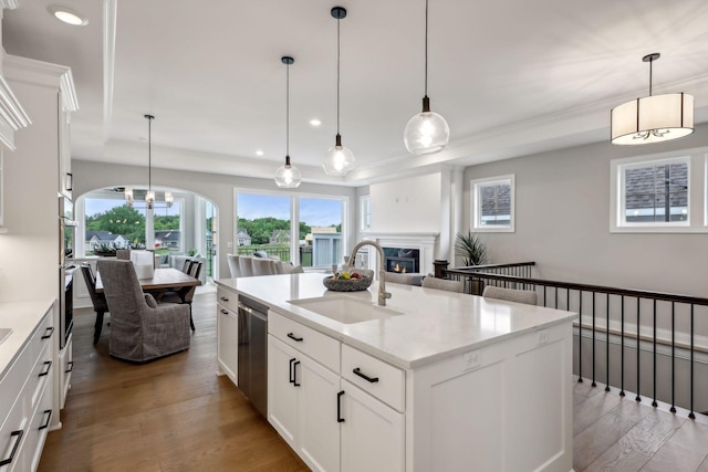 kitchen featuring dishwasher, a kitchen island with sink, hanging light fixtures, and sink