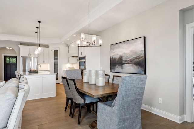 dining room featuring a notable chandelier, crown molding, sink, and dark hardwood / wood-style flooring