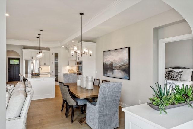 dining area featuring a notable chandelier, crown molding, sink, and light hardwood / wood-style flooring