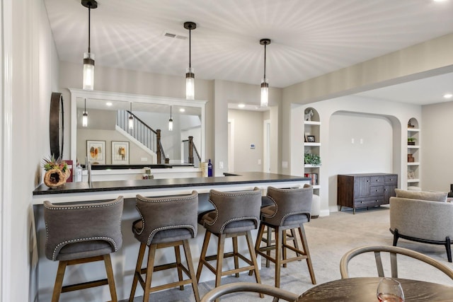 kitchen featuring light carpet, pendant lighting, built in features, and a breakfast bar