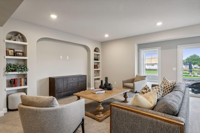 living room with built in shelves and light colored carpet