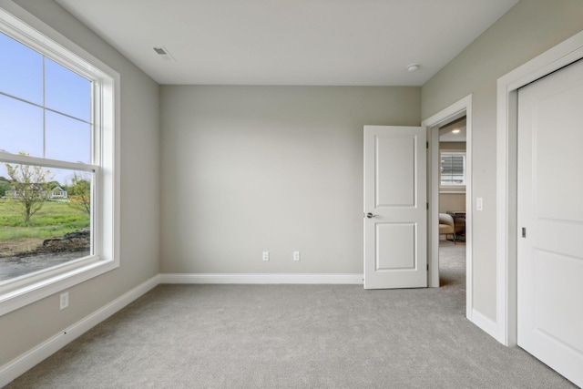 unfurnished bedroom featuring light carpet and multiple windows