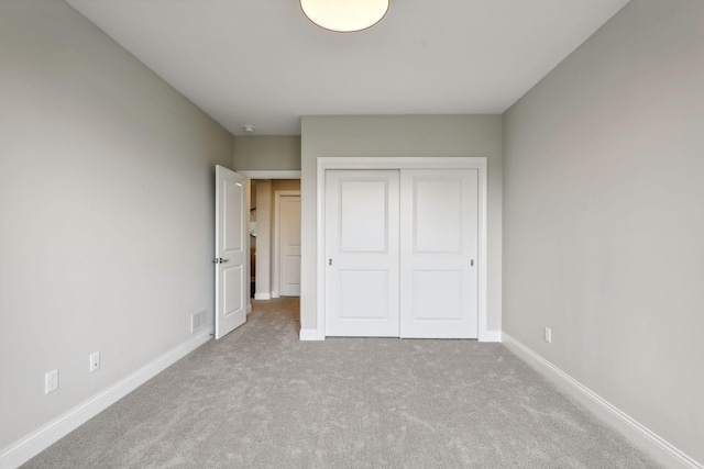 unfurnished bedroom featuring a closet and light colored carpet