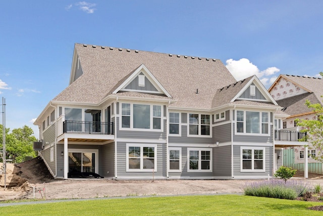 back of house with a balcony and a lawn