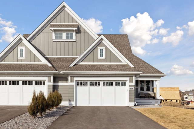 craftsman inspired home with aphalt driveway, board and batten siding, a garage, and roof with shingles