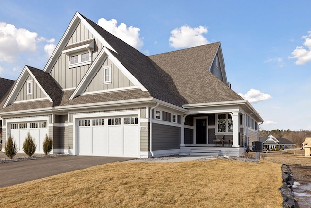 view of front of property with central air condition unit, a front lawn, driveway, a porch, and board and batten siding