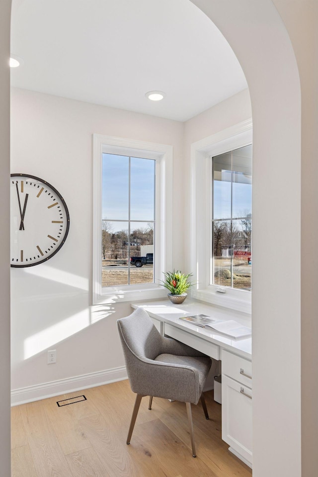 office featuring light wood finished floors, recessed lighting, arched walkways, and baseboards