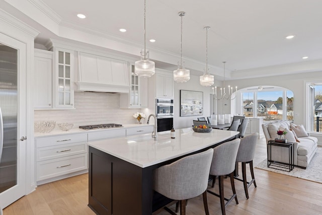 kitchen with a breakfast bar, a sink, tasteful backsplash, stainless steel appliances, and light wood finished floors