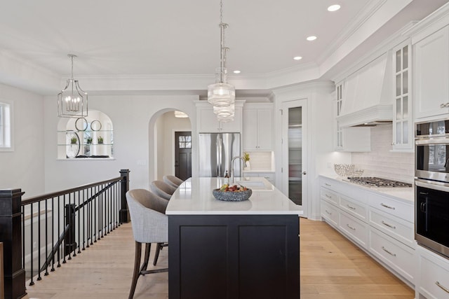 kitchen featuring premium range hood, a sink, white cabinetry, stainless steel appliances, and light countertops