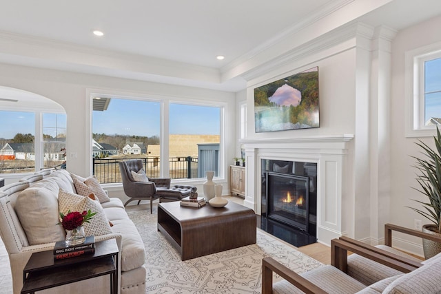 living area featuring baseboards, light wood-style flooring, a fireplace with flush hearth, recessed lighting, and ornamental molding