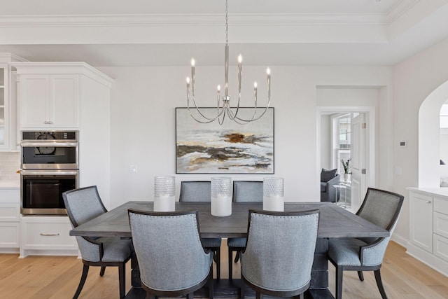 dining area featuring arched walkways, a notable chandelier, light wood-style floors, and ornamental molding