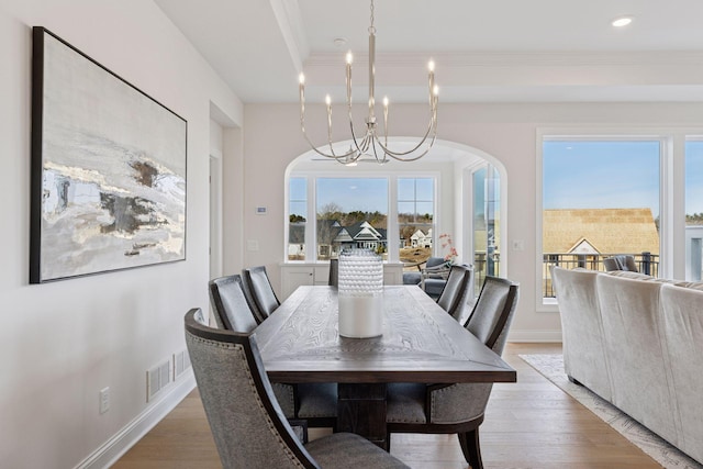 dining room featuring visible vents, light wood finished floors, baseboards, an inviting chandelier, and arched walkways