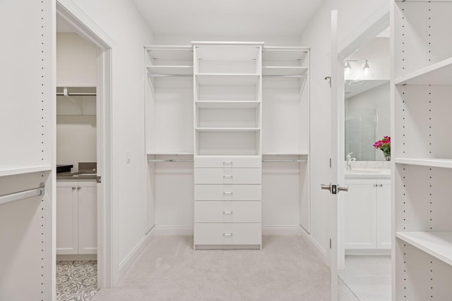 walk in closet with a sink and light colored carpet