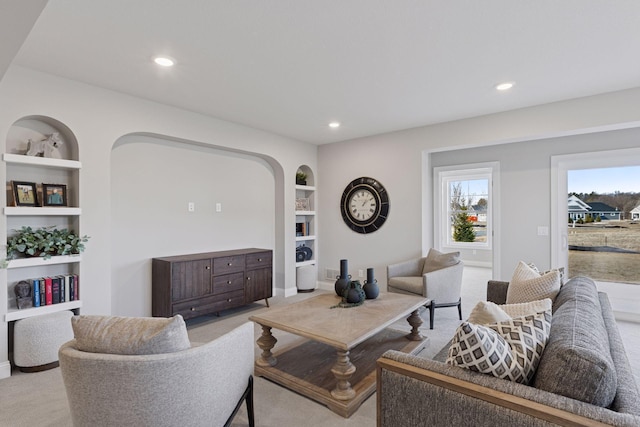 living area with built in shelves, recessed lighting, and light carpet